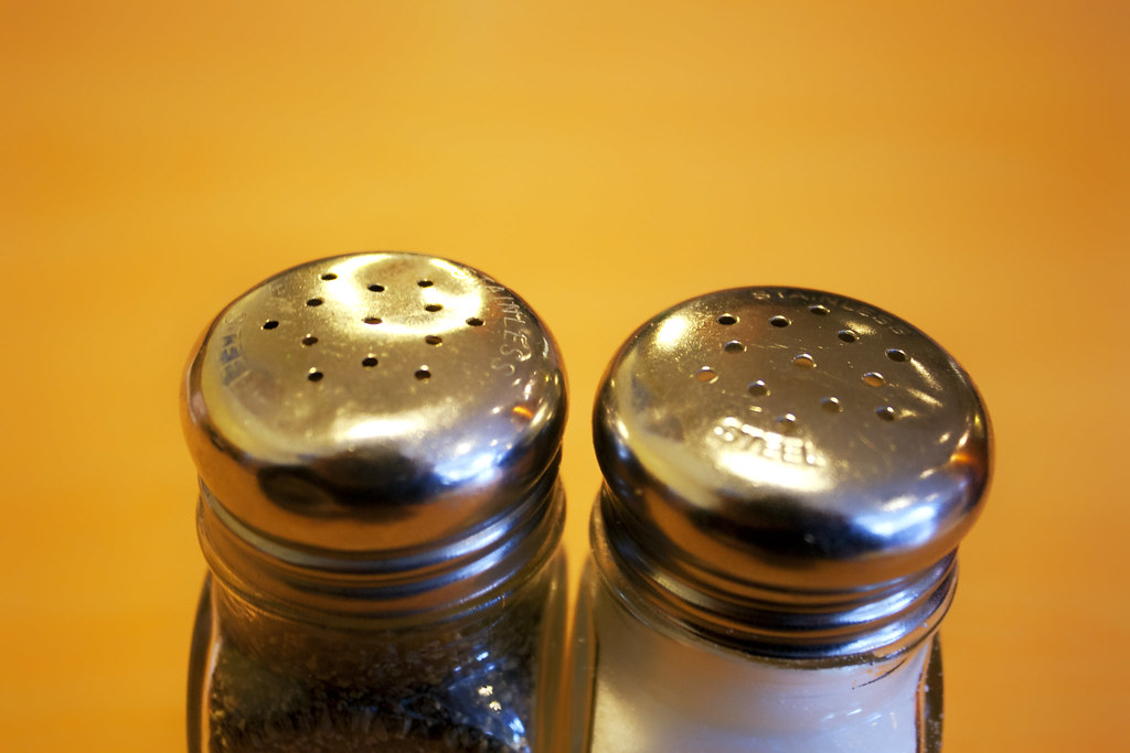 Salt and pepper shakers in front of a yellow background